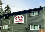 Thumbnail 4 of 25 - A green building with a sign that says Village Manor Apartments.