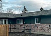 Thumbnail 10 of 25 - A house with a grey roof and a brick wall.