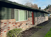 Thumbnail 13 of 25 - A green house with a red door and a red brick wall.