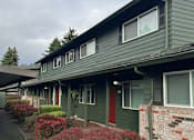 Thumbnail 12 of 25 - A green building with a red door and windows.