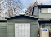 Thumbnail 6 of 25 - A green shed with a white door and a mailbox on the side.