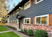 Thumbnail 1 of 47 - A house with a grey siding and a brick wall.