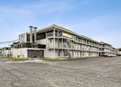 Thumbnail 11 of 25 - A large, multi-story building with a parking lot in front.
