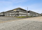 Thumbnail 10 of 25 - A large, multi-story building with a parking lot in front.