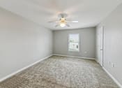 Thumbnail 18 of 25 - A room with a carpeted floor and a ceiling fan.