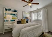 Thumbnail 8 of 32 - A bedroom with a white bed and a ceiling fan.