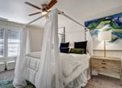 Thumbnail 9 of 32 - A bedroom with a canopy bed and a ceiling fan.