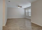 Thumbnail 19 of 32 - A room with a ceiling fan and wooden flooring.