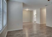 Thumbnail 18 of 32 - A spacious room with wooden flooring and white walls.