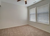 Thumbnail 20 of 32 - A room with a ceiling fan and carpeted floor.