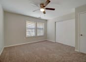Thumbnail 21 of 32 - A room with a ceiling fan and carpeted floor.