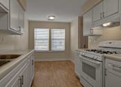 Thumbnail 4 of 32 - A kitchen with a stove, sink, and cabinets.
