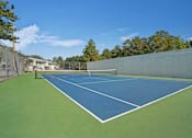 Thumbnail 22 of 32 - A tennis court with a blue surface and white lines.