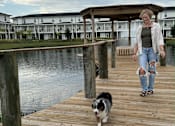 Thumbnail 3 of 45 - A woman walks her dog on a wooden dock.