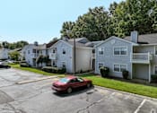 Thumbnail 24 of 29 - A red car is parked in a parking lot in front of a house at Sedgefield Square Apartments, North Carolina, 27407