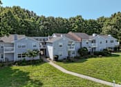 Thumbnail 23 of 29 - A row of white houses with green trees in the background at Sedgefield Square Apartments, Greensboro, 27407