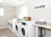 Thumbnail 20 of 29 - A row of white front load washing machines in a laundry room at Sedgefield Square Apartments, Greensboro
