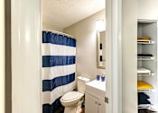 Thumbnail 11 of 29 - A bathroom with a blue and white striped shower curtain at Sedgefield Square Apartments, Greensboro, NC