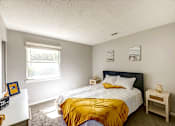 Thumbnail 7 of 29 - A bedroom with a bed, nightstand, and window at Sedgefield Square Apartments, Greensboro, NC, 27407
