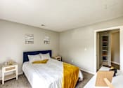 Thumbnail 6 of 29 - A bedroom with a bed, nightstand, and a yellow blanket at Sedgefield Square Apartments, North Carolina