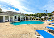 Thumbnail 18 of 29 - A pool area with a small building and lounge chairs at Sedgefield Square Apartments, Greensboro