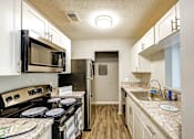 Thumbnail 2 of 29 - A kitchen with a black stove top oven and a black microwave above it at Sedgefield Square Apartments, North Carolina, 27407