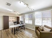 Thumbnail 15 of 29 - A room with a brown couch and a white desk at Sedgefield Square Apartments, North Carolina