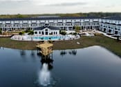 Thumbnail 2 of 45 - A large building with a pool and a dock in front of it.