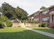 Thumbnail 5 of 16 - a grassy area with a walkway in front of a brick building at Willow Gardens Apartments, Teaneck, 07666