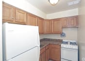 Thumbnail 10 of 16 - a kitchen with wooden cabinets and white appliances at Willow Gardens Apartments, Teaneck, NJ, 07666
