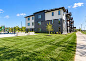 Thumbnail 68 of 71 - A modern apartment building with a grassy area in front.