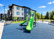 Thumbnail 8 of 71 - A playground with a green slide in front of a building.