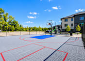 Thumbnail 9 of 71 - A basketball court with a blue and red surface and a basketball hoop.