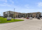 Thumbnail 1 of 22 - an empty parking lot with an apartment building in the background