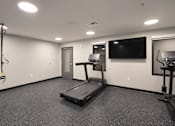 Thumbnail 16 of 71 - A spacious room with a treadmill, exercise bike, and television.