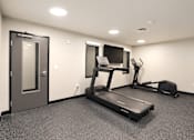 Thumbnail 10 of 71 - A room with a treadmill, exercise bike, and television.