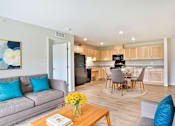 Thumbnail 1 of 4 - A living room with a grey couch and a wooden coffee table.