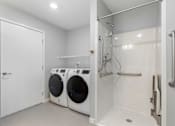 Thumbnail 21 of 22 - a washer and dryer in a laundry room with a shower and a door