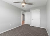 Thumbnail 16 of 22 - a bedroom with a ceiling fan and a door to a hallway
