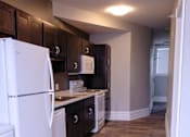 Thumbnail 4 of 9 - A kitchen with a white refrigerator and wooden cabinets.