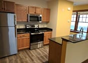 Thumbnail 1 of 29 - A kitchen with wooden cabinets and a black countertop.
