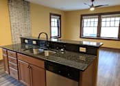 Thumbnail 2 of 29 - A kitchen with a black granite countertop and wooden cabinets.