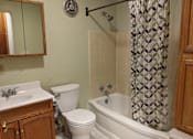 Thumbnail 13 of 15 - A bathroom with a toilet, sink, and bathtub.