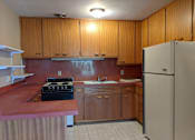 Thumbnail 7 of 15 - A kitchen with wooden cabinets and a refrigerator.