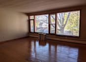 Thumbnail 6 of 15 - A room with wooden floors and windows overlooking a street.