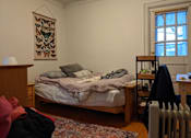 Thumbnail 8 of 9 - A bedroom with a bed, a radiator, and a rug.