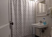 Thumbnail 9 of 9 - A bathroom with a white sink and a shower curtain with a pattern on it.