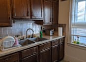 Thumbnail 5 of 9 - A kitchen with wooden cabinets and a white sink.