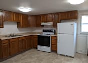 Thumbnail 26 of 29 - A kitchen with a white refrigerator and wooden cabinets.