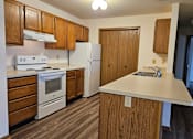 Thumbnail 3 of 11 - A kitchen with wooden cabinets and a white stove top oven.